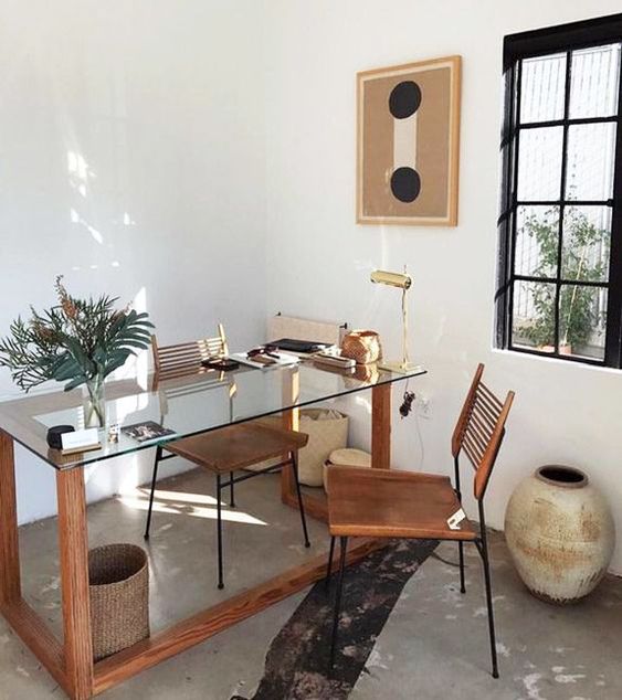ένας χώρος εργασίας boho με ένα γραφείο από γυαλί και ξύλο, μια δερμάτινη καρέκλα και πράσινο σε γλάστρες, μερικά βάζα και καλάθια